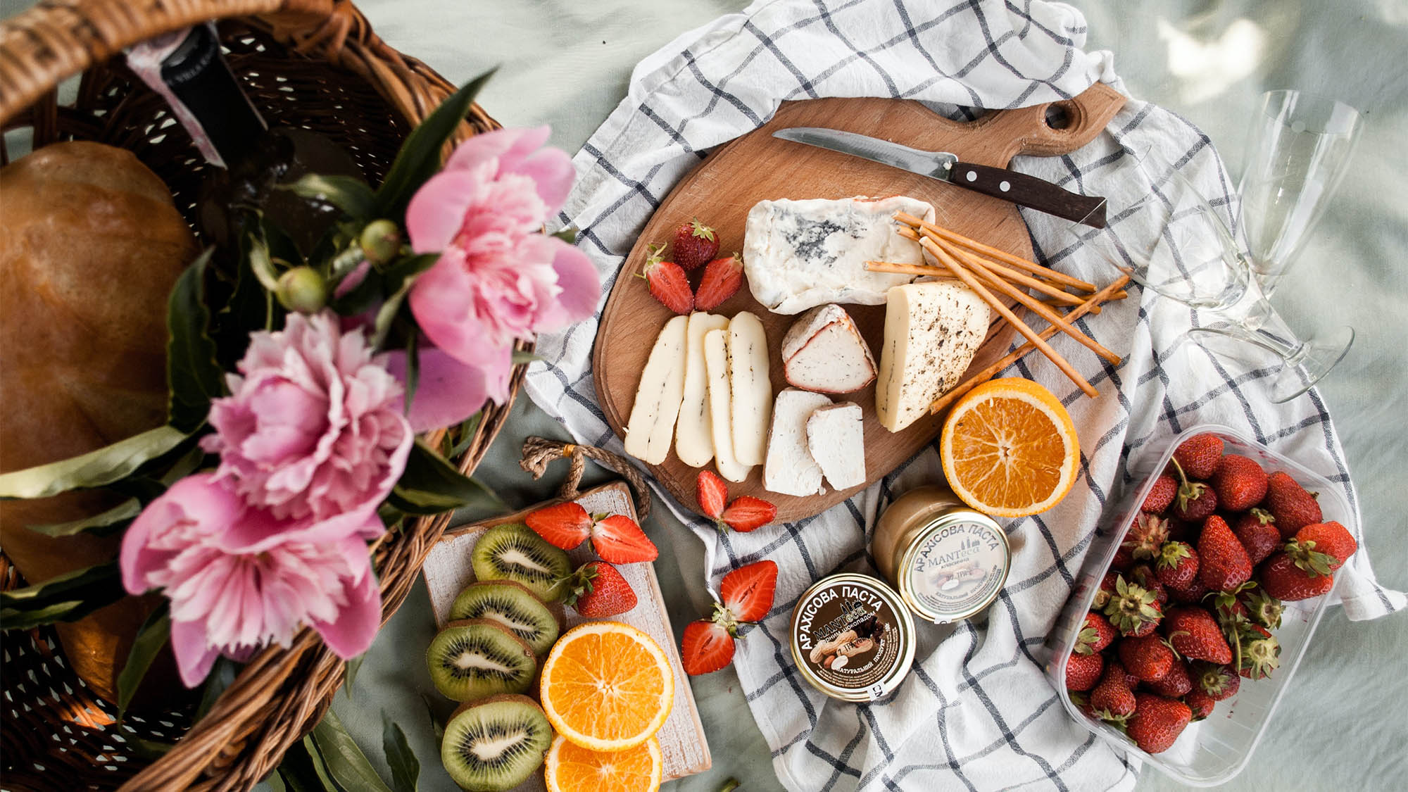 Charcuterie Board Atop Picnic Blanket with Flowers and Fruit