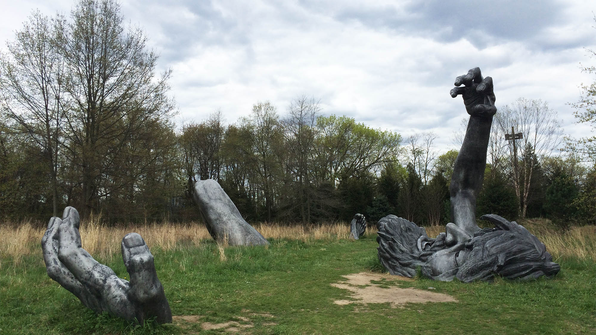 Giant outdoor sculpture where only man's left limbs and head pop out from the grass