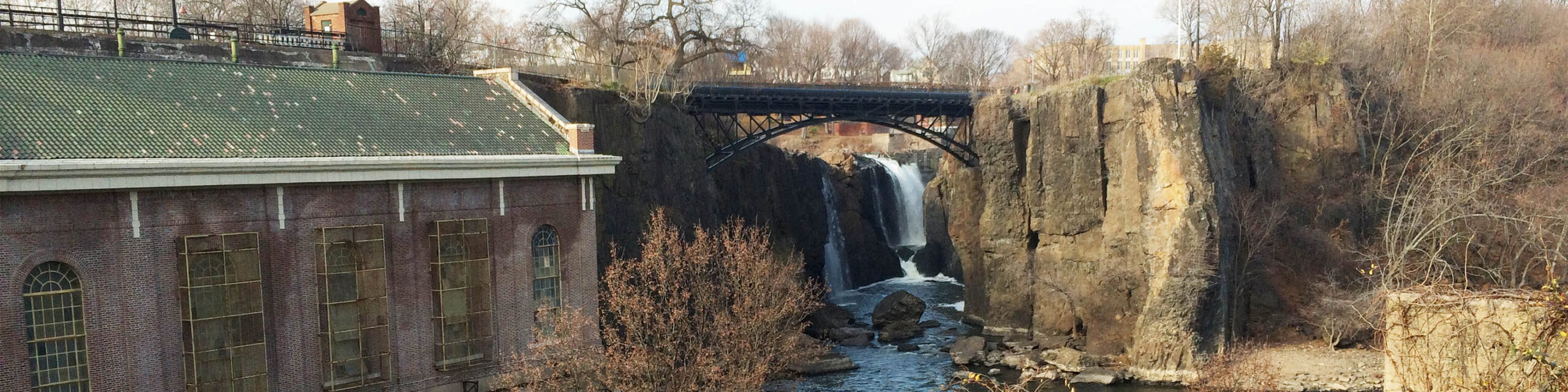 Waterfall under a bridge in Paterson New Jersey next to historic building