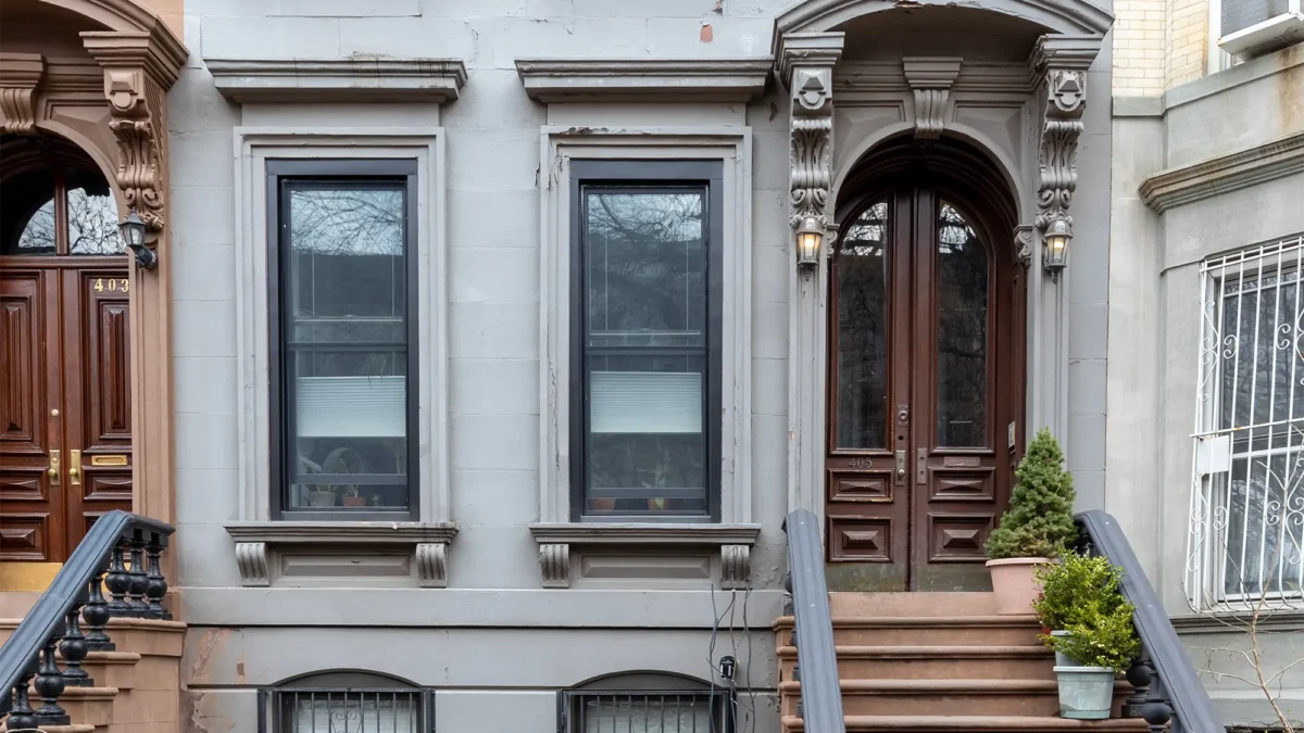 Gray prewar co-op exterior with arched door and stoop steps