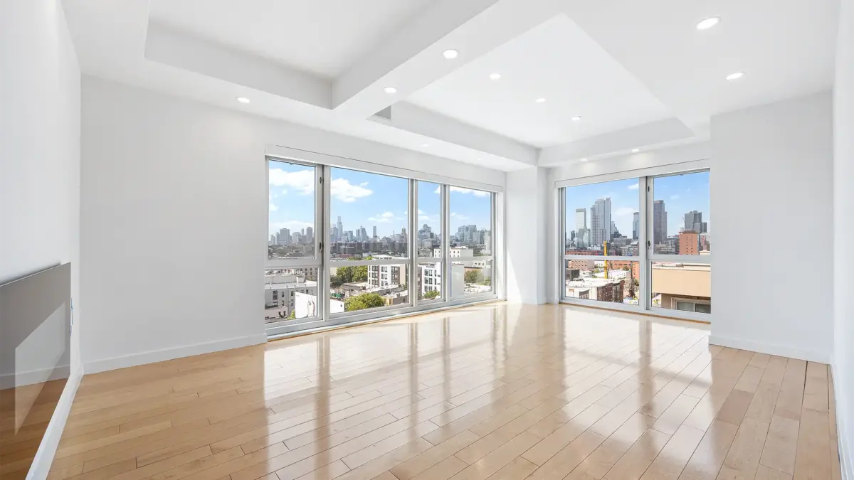 Empty living room with walls of windows looking over Brooklyn