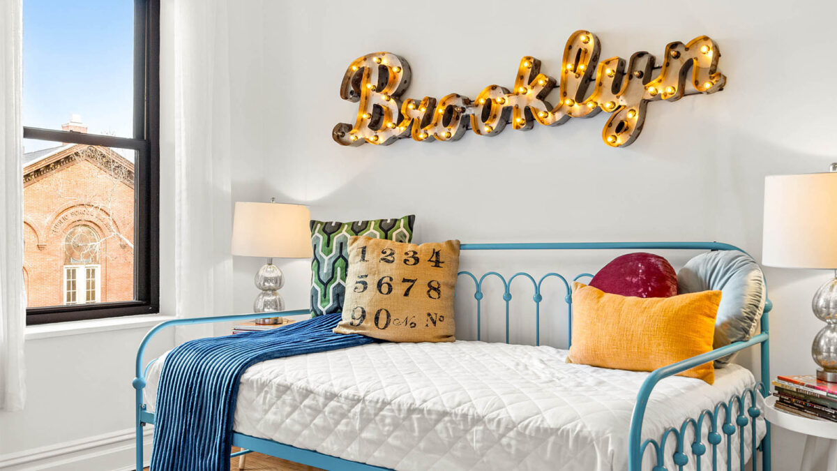 Staged kids bedroom with Brooklyn lit-up sign behind daybed