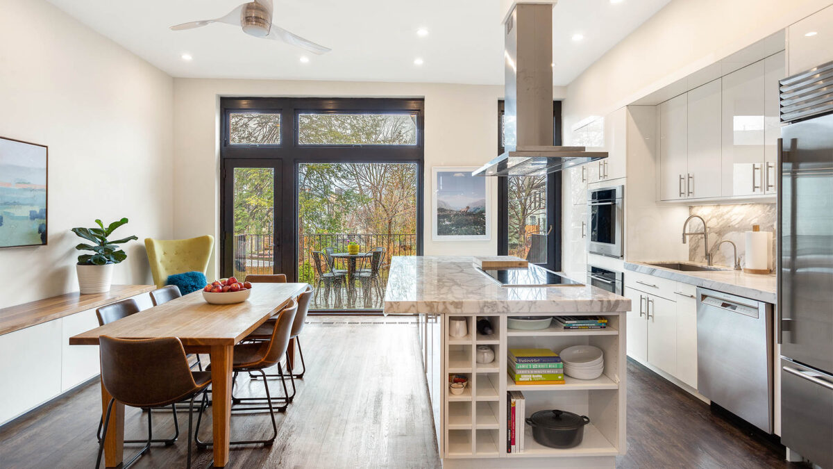 Staged minimalist kitchen with table on left and kitchen island on right