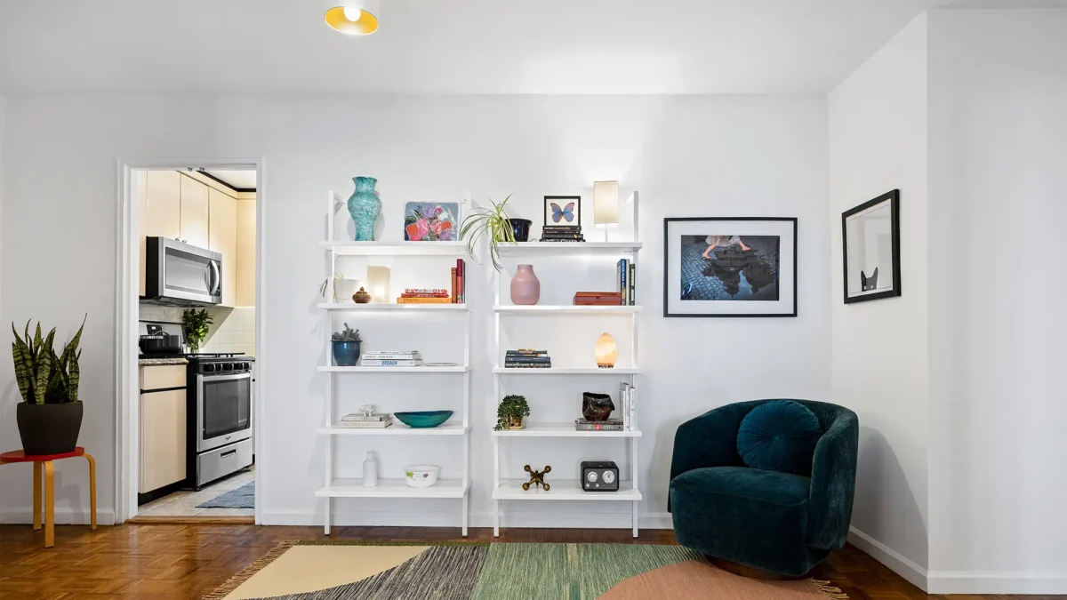 Minimalist staged living room with area rug, blue corner chair and white shelves