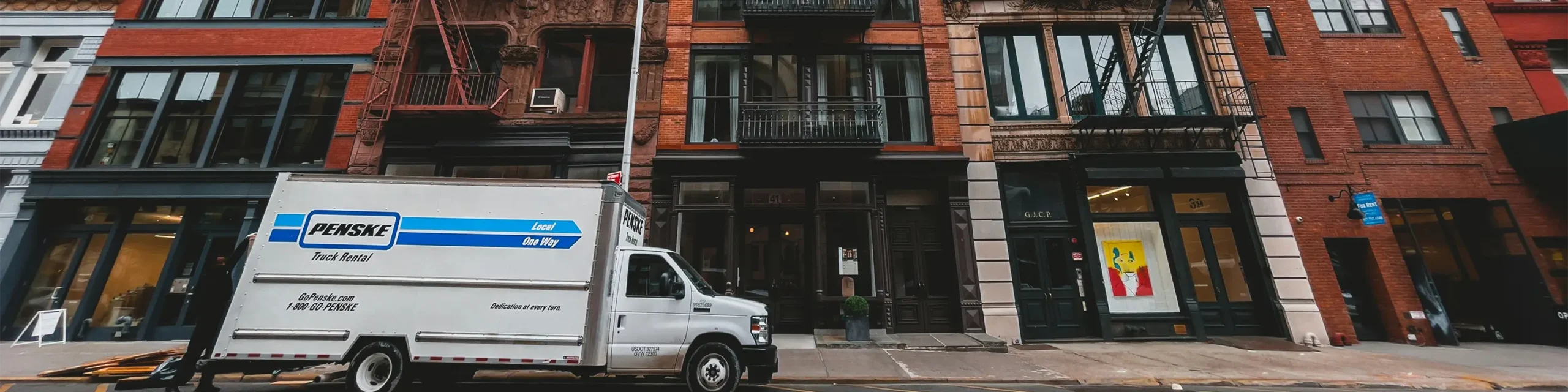 White Penske truck rental parked in front of NYC buildings